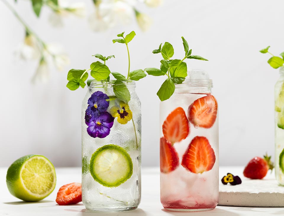 Cold Infused detox water with edible flowers, strawberry and mint leaves. Refreshing summer drink.