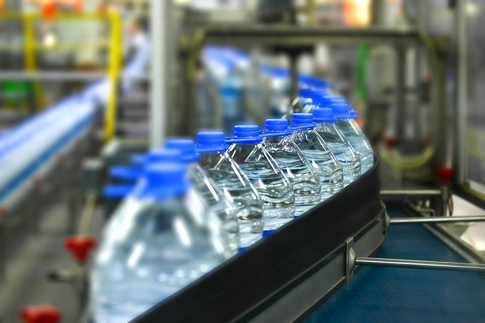 Mass production plastic water bottles in factory. Pet bottles on the marching band.